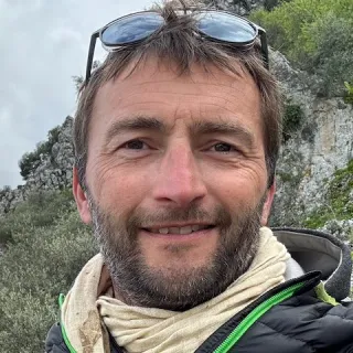 Portrait de Fred Tétart, souriant, en extérieur.